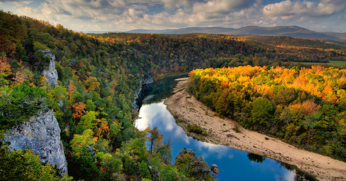 A wide view of the Buffalo National River in Arkansas. The trees show multiple colors, including green and yellow.