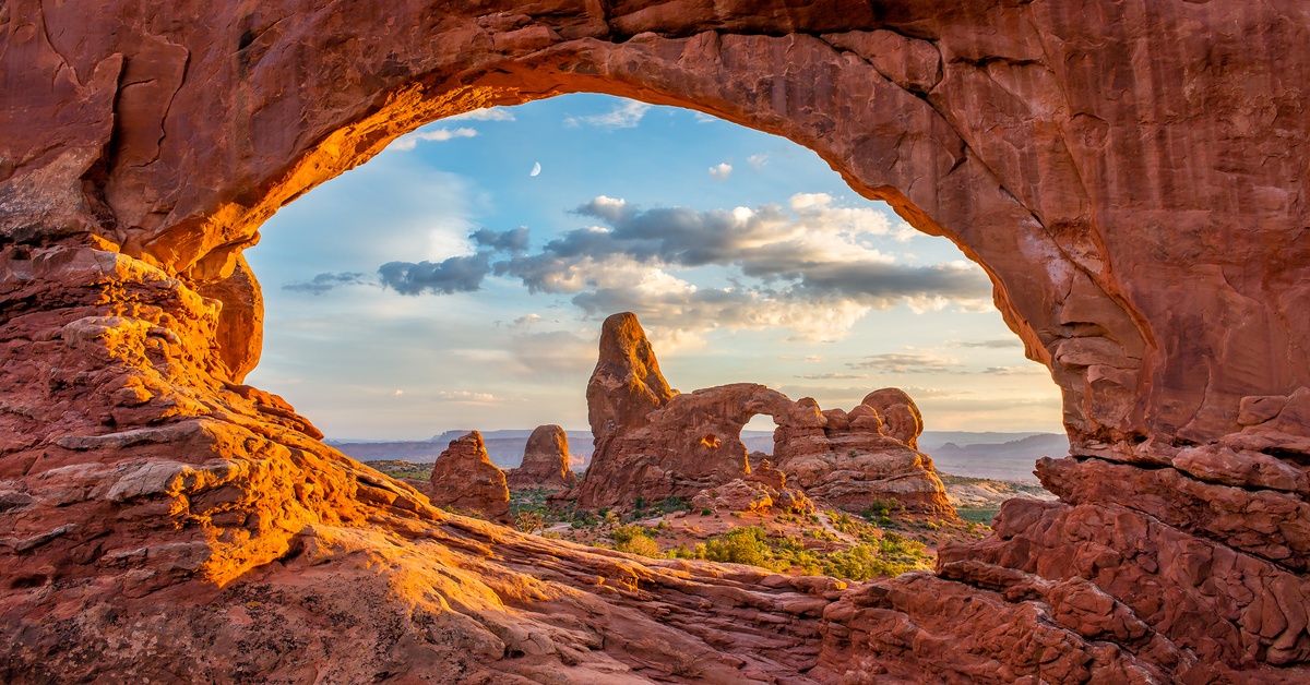 A view through a natural stone archway that is a part of Arches National Park in Utah. Another stone archway is behind it.
