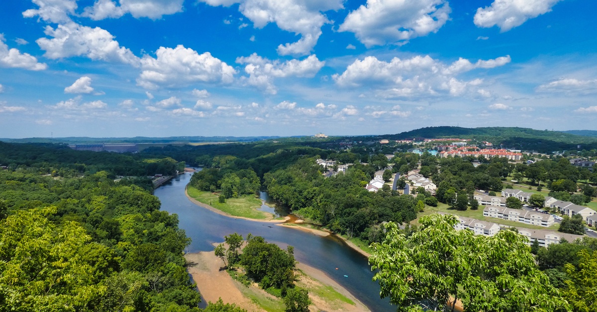 An aerial view of Branson, Missouri. Several white buildings are positioned next to a long river cutting through the land.