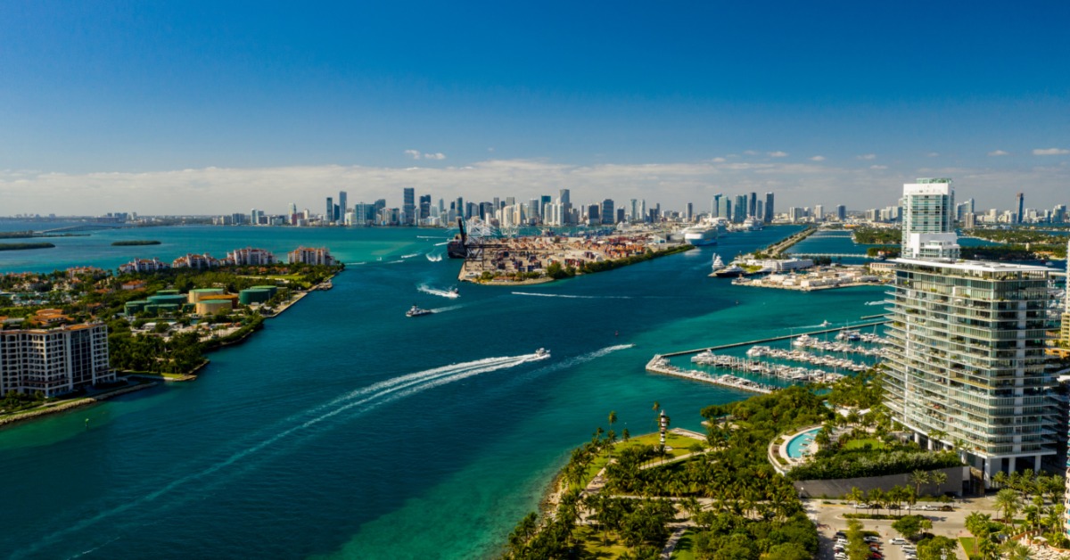 An aerial view of Miami Beach. There are several islands with ocean between them and a boat cutting through the water.