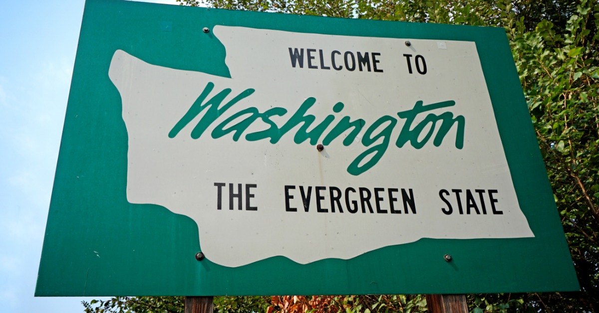 A large green sign that has the Washington state silhouette on it. It says "Welcome to Washington, The Evergreen State."