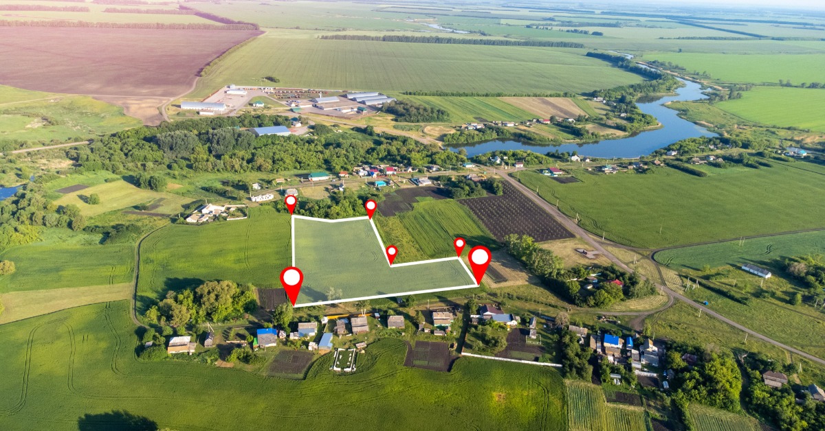 An aerial view of an open plot of land in the middle of some farmland. Red GPS markers outline the plot.