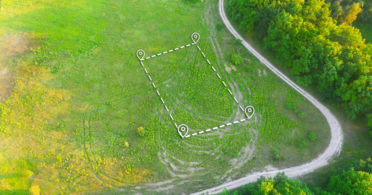 A top-down topographical view of an open plot of land. The land is outlined by a dotted square and four GPS markers.