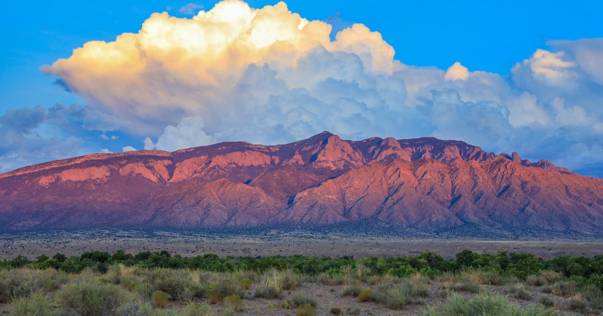 The Sandia Mountains in New Mexico. The mountains rise up in the background behind some dusty plains.