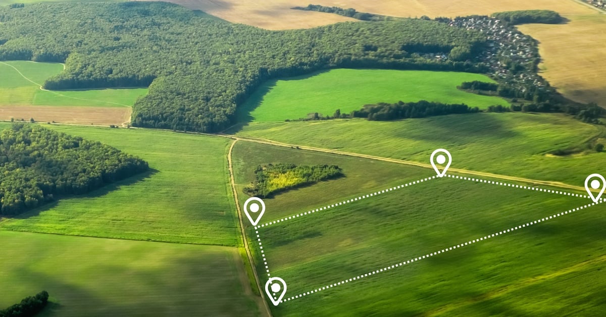 An aerial view of a large piece of land divided into various plots of green grass. A white dotted line outlines the area.